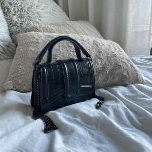 väska - perfekt väska till alla tillfällen, älskar storleken på denna!! det är en väska med en insperering av ormskinn med en svart kedja runt väskan. väskan kan användas i 3 st olika lägen💕 