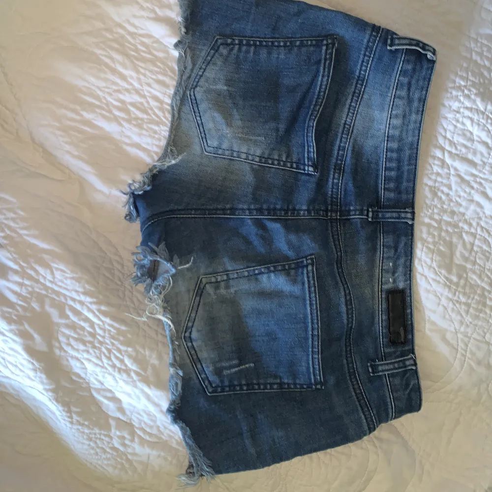 Säljer ett par snygga blåa lågmidjade jeansshorts från pieces. De har en cool distressed look med slitna detaljer och fransiga kanter. Perfekta för en avslappnad sommarstil! 🕶️skriv för fler bilder❤️. Shorts.