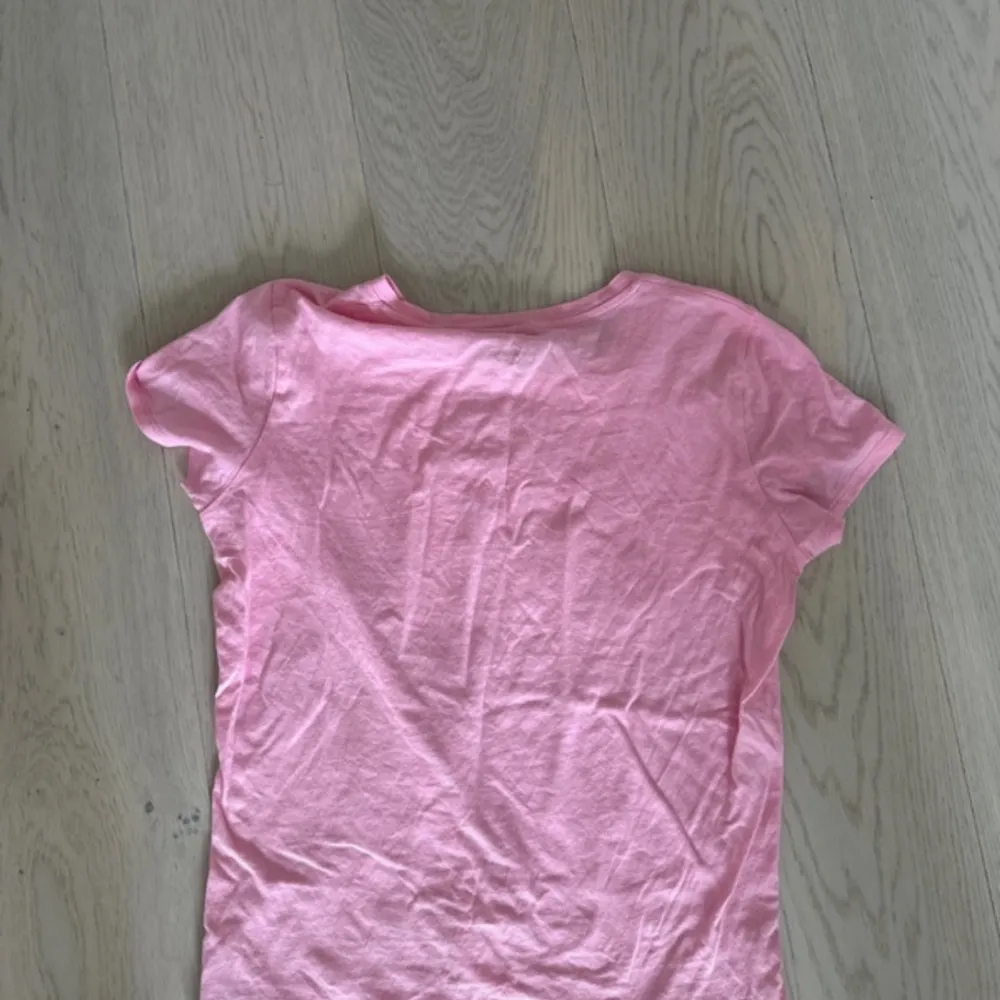 Säljer en superfin rosa t-shirt från Juicy Couture. Den har korta ärmar och ett glittrigt guldtryck med märkesnamnet på framsidan. Perfekt för en avslappnad men ändå stilren look. T-shirten är i bomull och känns riktigt skön mot huden.. T-shirts.