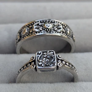 Vintage-inspirerade silverringar med blommönster - Säljer ett par superfina vintage-inspirerade silverringar med detaljerade blommönster. Den ena ringen har en fyrkantig topp med en blomma i mitten, medan den andra har ett runt band med blommor och små prickar runtom. Perfekta för att ge en bohemisk touch till din stil! både är strl 10 ( 19.8mm)
