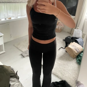 Svart ärmlös topp - säljer dessa svarta utsvängda tights. De är folded och viks alltså ner i midjan för en snygg stilren look. Passar lika bra till en lugn kväll hemma som snygga fest byxor.