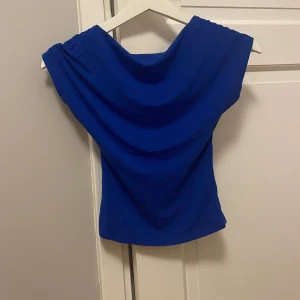 Blå topp - Säljer en snygg blå topp med korta ärmar. Den har en enkel och stilren design, perfekt för både vardag och fest. Materialet är mjukt och stretchigt, vilket ger en bekväm passform. storlek XS