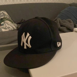 Svart fitted keps - En svart new era yankees keps som är fitted. Storlek 7 1/8. Den har snygg design på sidan och den har inga skador eller fläckar