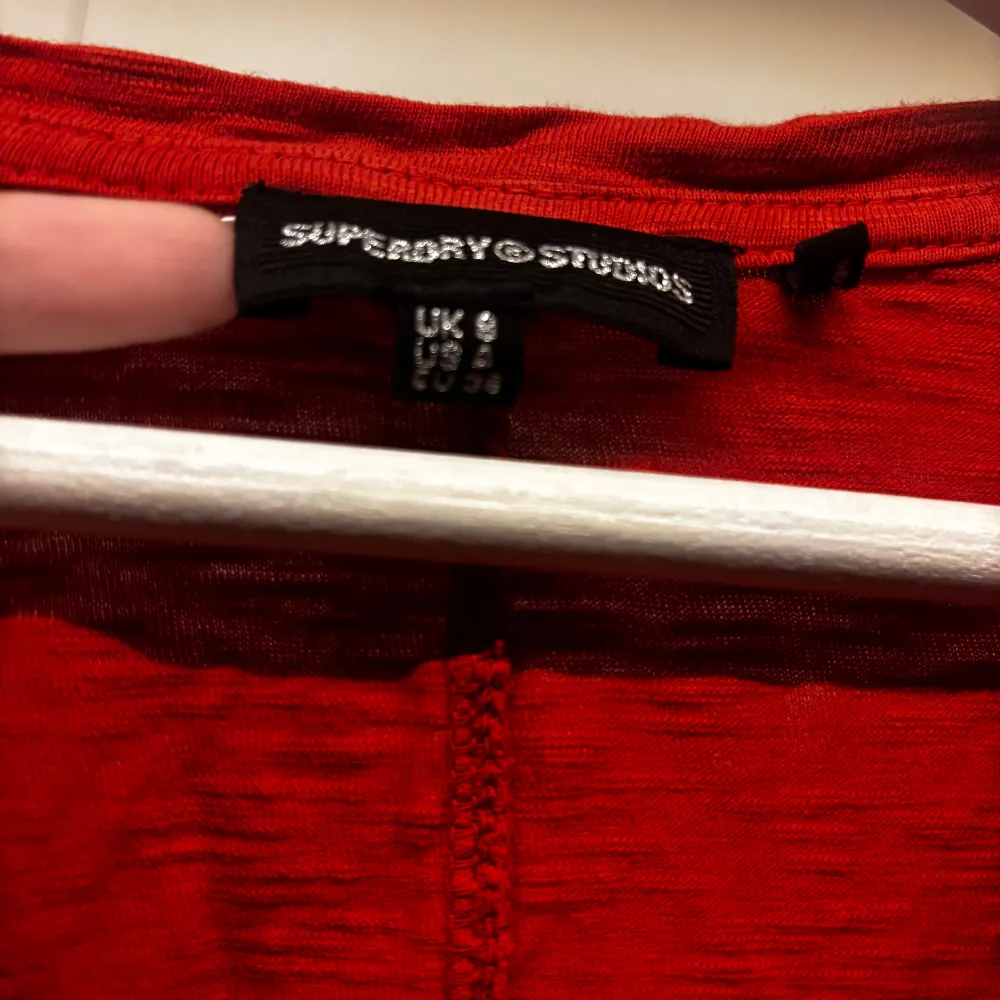 Säljer en snygg röd långärmad tröja från Superdry Studios. Den har en v-ringad hals och en liten bröstficka. Perfekt för höst och vår, och den är i mycket bra skick. Passar både till vardags och lite mer uppklädda tillfällen. 🧡. Tröjor & Koftor.