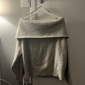 Beige offshoulder tröja - Superfin beige offshoulder tröja i stickat material. Perfekt för höst och vinter med sin mysiga och varma känsla. Den har långa ärmar och en loose passform som gör den extra bekväm. Perfekt för att mysa hemma eller en dag på stan! Är storlek L men passar till S M