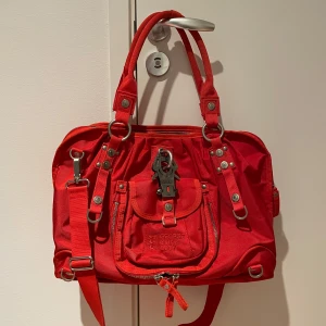 Röd axelväska från George Gina & Lucy - Snygg röd axelväska från George Gina & Lucy i mycket bra skick. Perfekt jobb/skolväska då dator får plats plus mer. Går att ha på axeln och som cross body. 