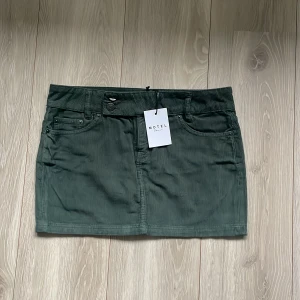 Grön manchesterkjol från Motel - Snygg grön manchesterkjol från Motel rocks i low rise modell. Perfekt för höst och vår, och kan stylas både upp och ner beroende på tillfälle. Den gröna färgen ger en härlig vintagekänsla!💚   (Den är aldrig använd då den var för liten och missade retur tiden) 
