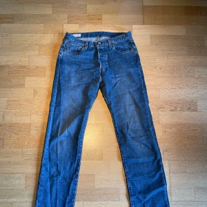 Blå Levis 501 jeans - storlek 30/32 - Säljer ett par klassiska blå Levi’s 501 jeans i nytt skick. Använda max 2 ggr. Jeansen har en knappgylf och straight passform. Kontakta gärna mig här på Plick ifall du har frågor. DEN FINNS KVAR. 