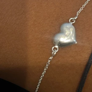 Silverarmband med hjärta - Snyggt och stilrent äkta silverarmband med ett hjärta i mitten. Perfekt för att ge en romantisk touch till din outfit. Kedjan är tunn och elegant, vilket gör det lätt att bära varje dag eller till speciella tillfällen. Ett måste för alla smyckesälskare! 💖Cubic Zirkon 1,5mm Storlek 21 x 18mm Längd 18cm Smycket är rhodinerat. Köpte armbandet för 1449 har inte haft länge. Om du vill komma med prisförslag funkar det också men bara vid snabbt köp