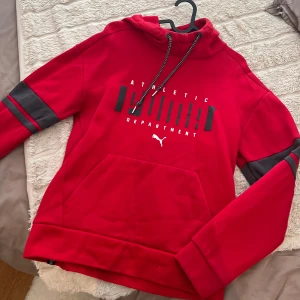 Röd puma Hoodie  - Röd huvtröja med svarta detaljer. Tröjan har en stor logga på framsidan. Använd fåtal tillfällen och är i mycket bra skick! 