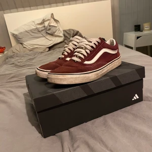 Vinröda sneakers från Vans - Säljer ett par snygga vinröda Vans sneakers i mocka med vita detaljer och snörning. De har en klassisk design med vit sula och är i bra skick, perfekta för vardagsbruk. Skostorleken är herr 43. Passar perfekt till jeans!