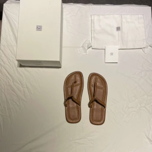 Totême Studio Sandaler - Totême T-strap sandaler Limited Edition. Skick 10/10 helt oanvända. Givetvis Äkta. Återsäljs för 400-560€. Allt original medföljer. Pris kan diskuteras!