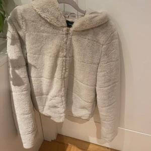 Beige pälsjacka  från ONLY - Mysig beige teddyjacka från ONLY i storlek XS. Jackan har en fluffig och varm känsla med dragkedja framtill. Sparsamt använd med en liten fläck framtill som säkert går att få bort 