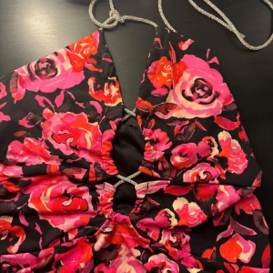 Blommig topp bikbok - Jättesöt blommig topp med glotterdetaljer på snöret, jättefin att ha som festtopp. Storlek s men funkar även för xs inga skador eller så, aldrig använd☺️