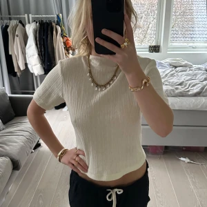 Vit ribbad topp - Säljer en stilren vit ribbad topp i mycket bra skick. Den har en tight passform och korta ärmar, perfekt för både vardag och fest. Toppen är tillverkad i Turkiet och är superbekväm att bära. Passar perfekt till jeans eller kjol för en chic look! Märket är ZARA och det är storlek L. Den är mer XS/S om mana vill ha den som jag har på bilden. Använd en gång