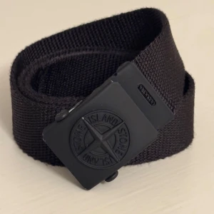 Bälte Stone Island - Säljer ett snyggt svart bälte från Stone Island. Bältet har svart spänne med Stone Island loggan. Storlek 3. 