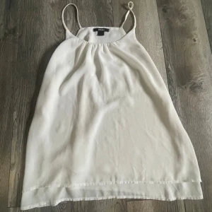 Vitt linne från esmara - Säljer ett enkelt och stilrent linne från esmara. Den är axelbandslös med tunna axelband och har en luftig passform. Perfekt för sommardagar eller som en bas i garderoben. Linnet är i mycket bra skick och gjord av ett lätt och bekvämt material.