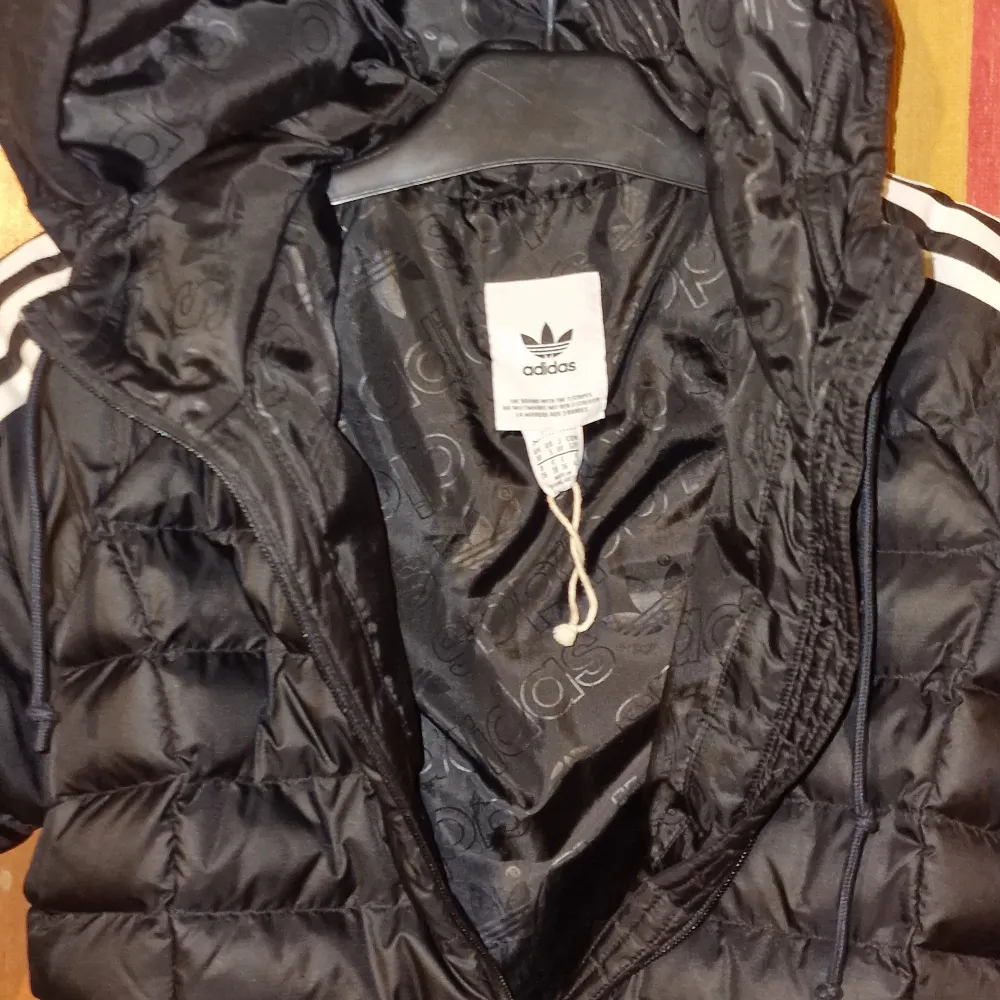 Säljer en snygg svart dunjacka från Adidas i mycket bra skick. Jackan har de klassiska tre ränderna längs ärmarna och en dragkedja framtill. Perfekt för höst och vinter, håller dig varm och stilren. Storleken är S . Passar både till vardags och sportiga aktiviteter. Är ny bara provad, men var för liten för grabben.. Jackor.