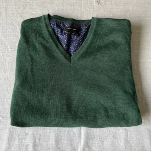 Grön merinoulltröja från Sand - Säljer en snygg grön tröja i 100% merinoull från Sand. Den har en stilren v-ringning och är perfekt för både höst och vinter. Tröjan är i mycket bra skick och passar perfekt för en elegant vardagslook. Supermjuk och bekväm!