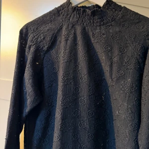 Svart långärmad topp från Free/Quent - Säljer en elegant svart topp från Free/Quent i storlek S. Den har ett vackert mönster och långa ärmar med smockdetaljer vid hals och ärmslut. Perfekt för höst och vinter, både till vardags och fest. 🖤