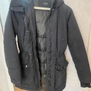 Svart vinterjacka från Everest - Säljer en svart vinterjacka från Everest i mycket bra skick. Jackan har en långärmad design med dragkedja och knappar framtill. Den är perfekt för kalla vinterdagar och har en skön, vadderad insida för extra värme. Storleken är dam 34 alltså xs och s. Den är väldigt lik canada goose parka och den sitter jätte fint på och är skön på insidan. Päls ingår också om man vill :) ny pris var 1600kr