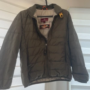 Grön quiltad jacka från Parajumpers - Säljer en snygg grön quiltad jacka från Parajumpers i bra skick. Den har en dragkedja framtill och två praktiska fickor med dragkedjor. Perfekt för höst och vår, med en cool patch på ärmen. Jackan är lätt och bekväm. Passar både till vardags och lite mer uppklädda tillfällen. Köpt för 3000kr I NK.