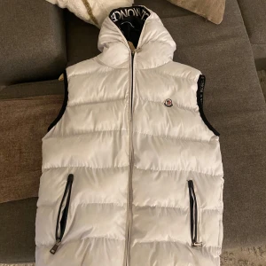 Moncler Väst med luva (Vit) - Säljer min Moncler väst med luva. Storlek L men passar även mig riktigt bra som bär M. Knappt använd 10/10 skick. Ge prisförslag