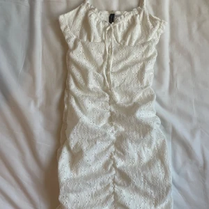 Vit klänning från H&M Divided - Säljer en söt vit klänning från H&M Divided i storlek XS. Klänningen har ett fint broderat mönster och knytning fram. Perfekt för sommarens alla fester eller en mysig dag på stan! (Oanvänd) 😍💓