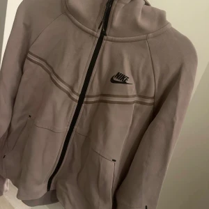 Beige hoodie från Nike Tech , st S  - Säljer en snygg beige hoodie från Nike i mycket bra skick. Den har en dragkedja framtill och en klassisk Nike-logga på bröstet. Perfekt för höst och vår, med en bekväm passform och långa ärmar. Grym för både chill och träning! Jättefint skick 