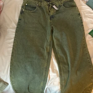Gröna jeans från PrettyLittleThing - Säljer ett par gröna jeans från PrettyLittleThing i storlek UK 12. De har en loose passform och är perfekta(40) för en avslappnad stil. Jeansen har klassiska fem fickor och en knappgylf. Perfekta för både vardag och fest!obs en av bälte hållarna är sönder men det märks inte och det går att sy.