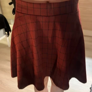 Rutig vinröd kjol stl L - Säljer en rutig vinröd kjol i kort modell. Bilden visar inte färgen bra, den är mer vinröd i verkligheten.