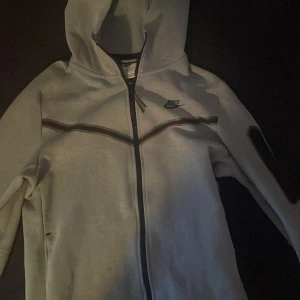 Nike tech fleece - Säljer en grå Nicke Tech Fleece. Storlek M. Äldre modellen. Den har gått sönder en gång längst ner i mitten men är nu sydd och resten av tröjan är i perfekt skick