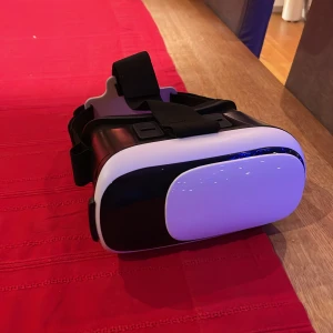 Svart och vit VR-headset - Säljer ett VR-headset i svart och vitt med justerbara remmar för bekväm passform. Perfekt för att uppleva virtuell verklighet hemma. Kompatibel med de flesta smartphones. Perfekt för att se filmer i 3d eller uppleva andra 3d upplevelser. Knappt använd och i bra skick