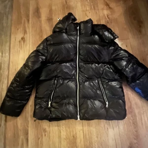 Lager 157 jackan Svart pufferjacka - Säljer en svart pufferjacka med dragkedja framtill och två fickor med dragkedjor. Jackan har en hög krage och är perfekt för kyligare väder. Inte använd en enda gång, helt ny. 
