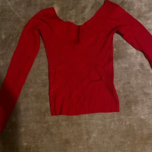Röd ribbad topp från H&M - Säljer en snygg röd ribbad topp från H&M med långärmad design och v-ringad hals. Perfekt för att lägga till en färgklick i garderoben. Passar bra till både jeans och kjol.