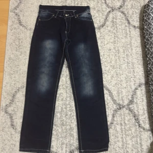 Mörkblå jeans med kontrastsömmar - Snygga mörkblå jeans med kontrastsömmar och coola detaljer på bakfickorna. Perfekta för en avslappnad stil med en touch av edge. De har en klassisk femficksdesign och en bekväm passform.
