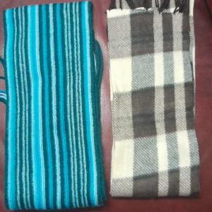 Två halsdukar i olika mönster 30 kr styck  - Säljer två snygga halsdukar. Den ena är randig i olika nyanser av blått och grönt, medan den andra är rutig i beige och grått. Perfekta för att hålla dig varm och stilren under kyliga dagar.
