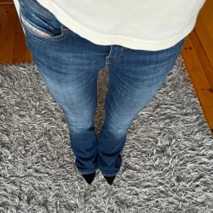 Blå lågmidjade bootcut jeans diesel - Snygga blå bootcut jeans med en klassisk look. De har en normal passform och är perfekta för en avslappnad stil. Jeansen har en dragkedja och knapp framtill. Står w24