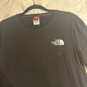 Svart t-shirt från The North Face - Snygg svart t-shirt från The North Face med tryck av berg och texten 'Never Stop Exploring' på baksidan. Perfekt för äventyrslystna! Den har korta ärmar och en klassisk rund halsringning. storlek S från dam, köpt i JD sports. skriv vid intresse! använt i några timmar