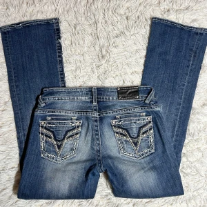 Lågmidjade bootcut jeans med hål och detaljerade bakfickor - Lågmidjade bootcut jeans. Storlek 7/8 längd 33. Skulle säga att detta motsvarar en stor s eller en m. Innerbenslängd:81 midjemått:40. Har inga bilder på då de är alldeles för stora. Köp sker via köp nu, jag postar inom 24h. Kvar tills markerad såld 