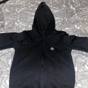 Svart huvtröja från Moncler - Snygg svart huvtröja från Moncler med dragkedja och huva. Tröjan har en diskret logotyp på bröstet och är perfekt för en stilren look. Tillverkad i ett mjukt material för extra komfort.