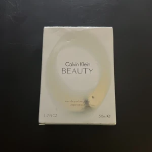 Calvin Klein Beauty Eau de Parfum - Elegant och sofistikerad parfym från Calvin Klein. Flaskan har en modern design med en oval form och silverdetaljer. Innehåller 50 ml av en blommig och feminin doft som passar perfekt för den stilmedvetna.