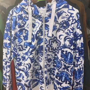 Blåvit mönstrad hoodie från Medicine - Säljer en snygg blåvit hoodie från Medicine med ett unikt blommönster. Hoodien har dragkedja och justerbar huva med snören. Perfekt för en avslappnad stil.