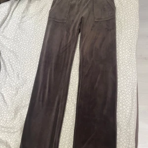 Mörgråa juicy couture mjukisbyxor  - Mörkgråa mjukisbyxor i ett mjukt material med bred resår i midjan. Byxorna har fickor både fram och bak med knappar. I mycket bra skick förutom att metal sakerna ramlat av vid snörena. Därav priset nypris 1200kr. Vill man ha fler bilder så skriv privat. 