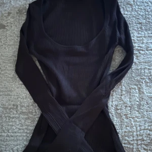 Svart ribbad tröja  från BikBok - Snygg svart ribbad tröja  från BikBok i storlek XS. Tröjan  har en åtsittande passform med långa ärmar och en djup rundad halsringning. Perfekt för en stilren look.