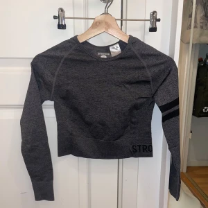 Grå långärmad tröja från Stronger - Snygg grå långärmad tröja från Stronger med svarta detaljer på ärmen. Tröjan har en tight passform och är tillverkad i ett mjukt och stretchigt material.