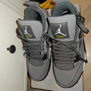 Grå Nike Air Jordans - Snygga grå Nike Air Jordans med svarta och vita detaljer. Skorna har snörning och en ikonisk Jumpman-logga på tungan och hälen. Perfekta för dig som vill ha en stilren och sportig look.