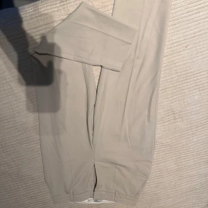 Beige kostymbyxor från NA-KD - Snygga beige kostymbyxor från NA-KD med en stilren design. Byxorna har en högmidjad passform och stängs med en diskret dragkedja och hyska. Perfekta för en chic och elegant look.