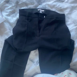 Svarta kostymbyxor - Snygga svarta kostymbyxor (mid rise) och rak passform med slits samt fickor. Perfekta för en stilren look. Byxorna har en dragkedja framtill och är tillverkade i ett bekvämt material. De är aldrig använda då planen va att jag skulle sy upp de men nu har de även blivigt för små i midjan. Jag är 157cm lång😊