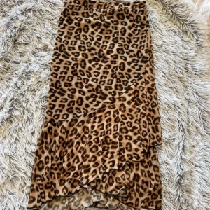 Leopardmönstrad kjol - Snygg leopardmönstrad kjol med volangdetaljer. Kjolen har en asymmetrisk design som ger en trendig look. Perfekt för att sticka ut i mängden!